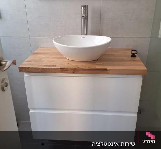 כיור עגול על משטח עץ בחדר אמבטיה